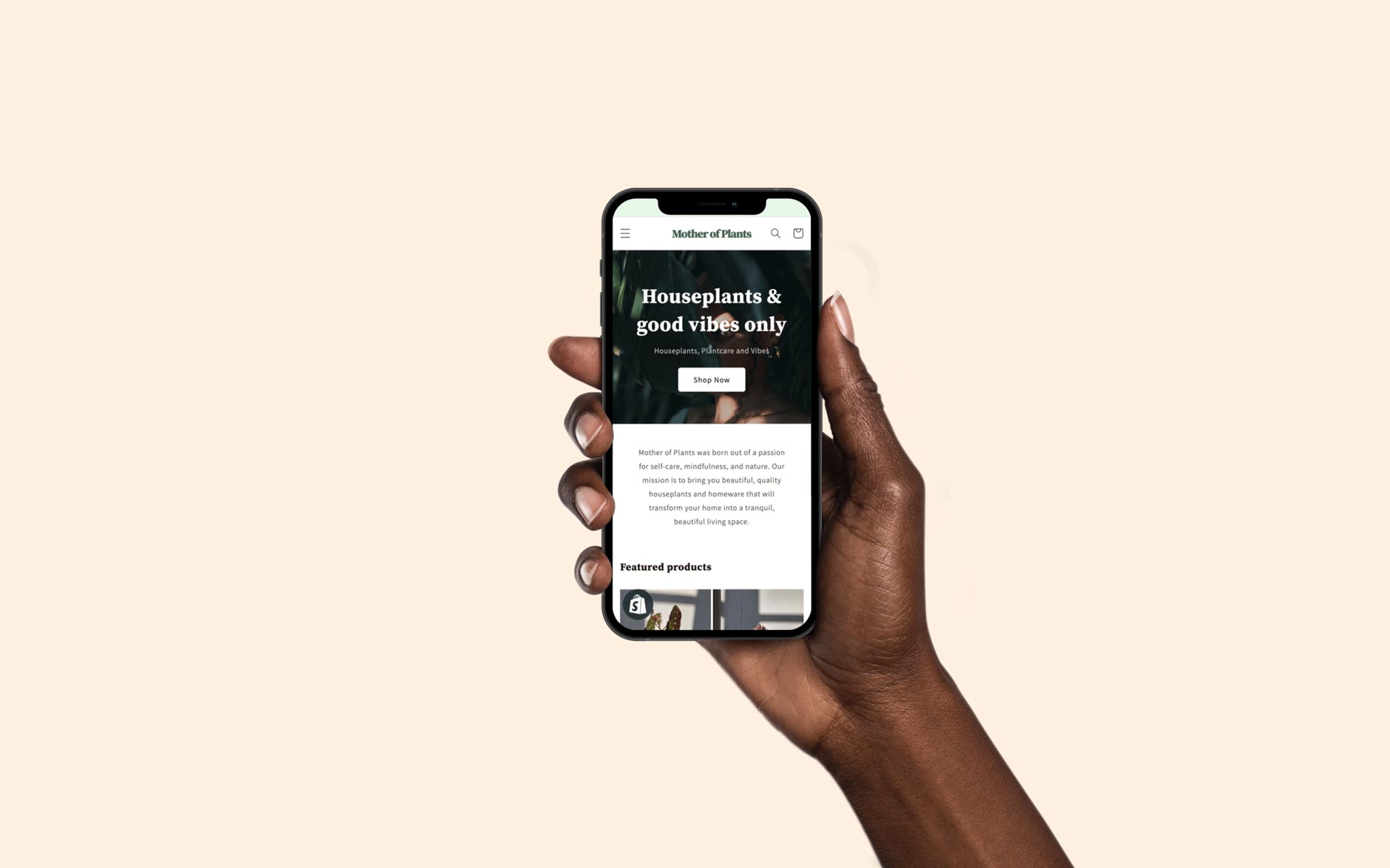 Photograph of a hand holding an iphone displaying the Mother of Plants Online Store Home page designed by Can O' Baked Beans 2020